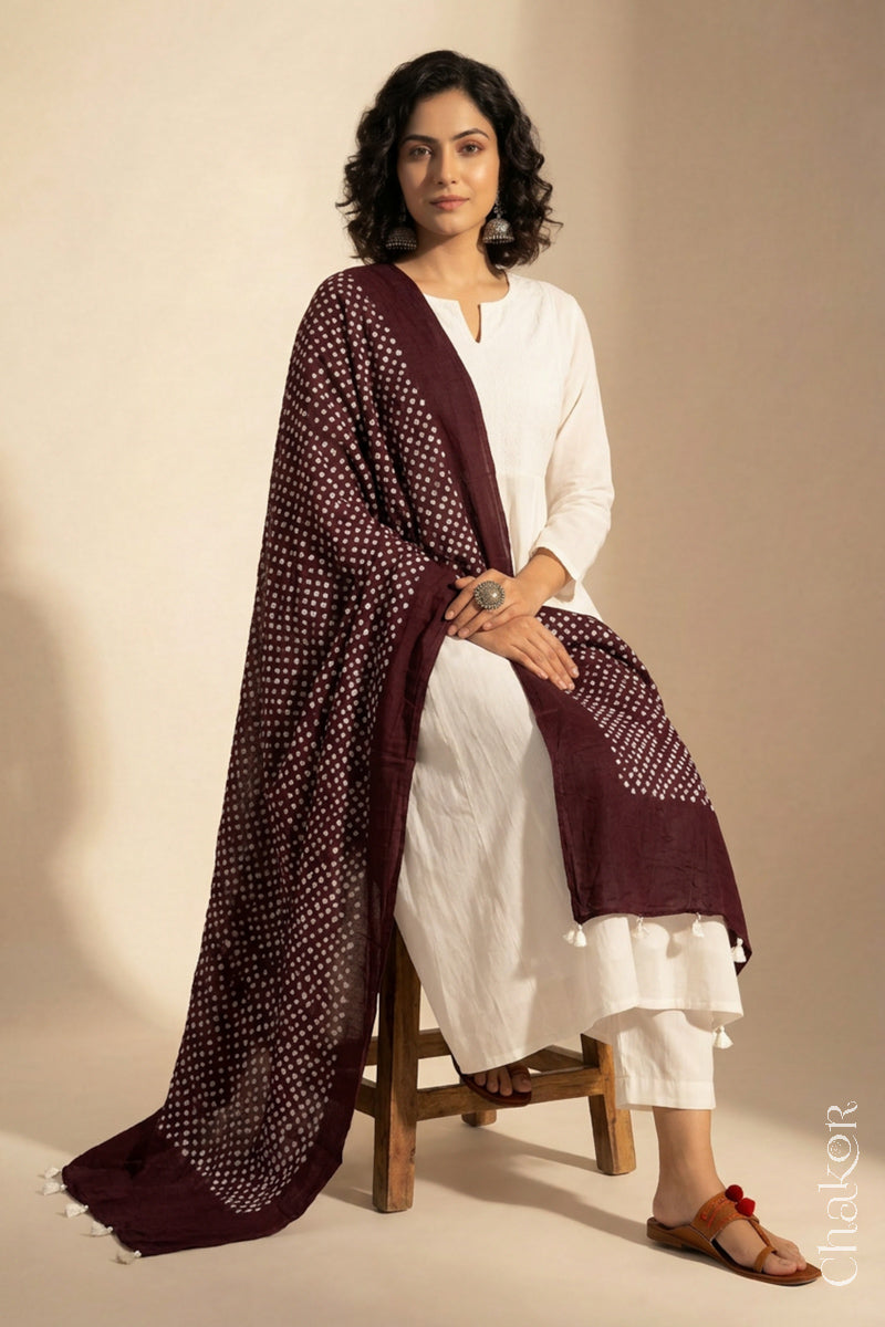 Model wearing Dark maroon Bandhani mul cotton dupatta with tie-dye dot pattern draped over a white kurta.

