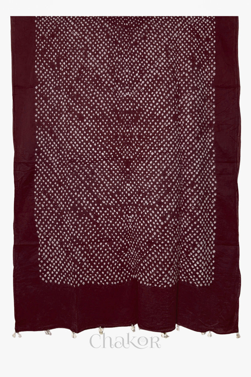 Full-length flat view of Dark maroon Bandhani mul cotton dupatta with all-over tie-dye pattern and tassels.
