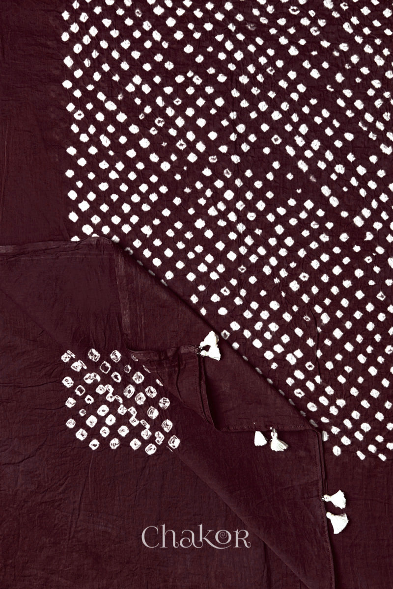 Corner detail of Dark maroon Bandhani mul cotton dupatta showing pallu tasseled edge and tie-dye motifs.
