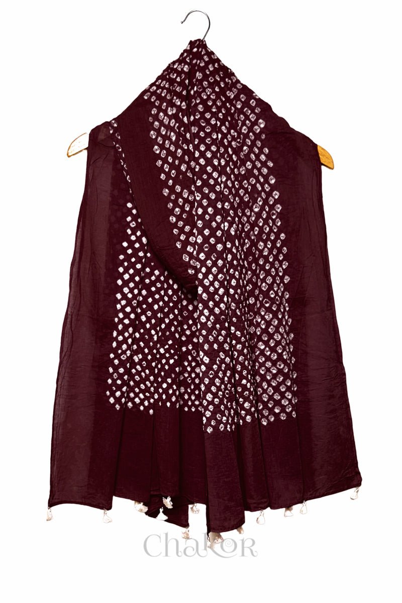 Dark maroon Bandhani mul cotton dupatta draped on hanger showing tie-dye dot pattern and tasselled edge.

