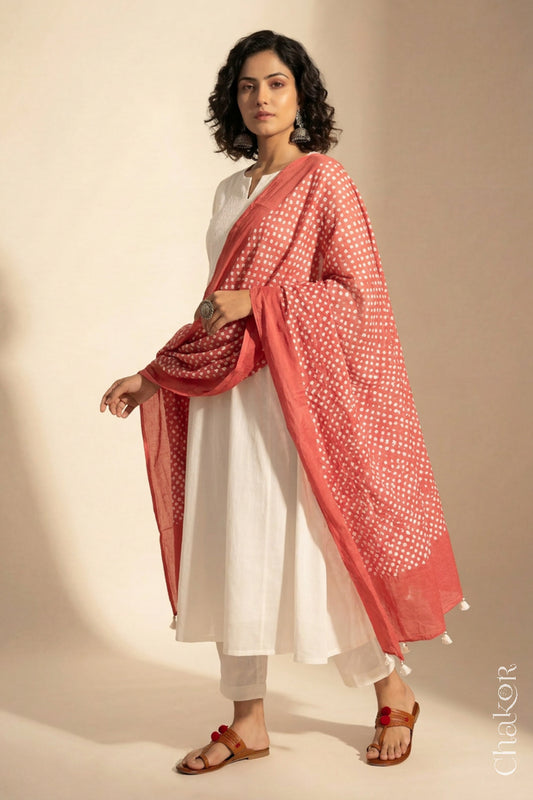 Model wearing Dark Peach Bandhani mul cotton dupatta with tie-dye dot pattern draped over a white kurta.
