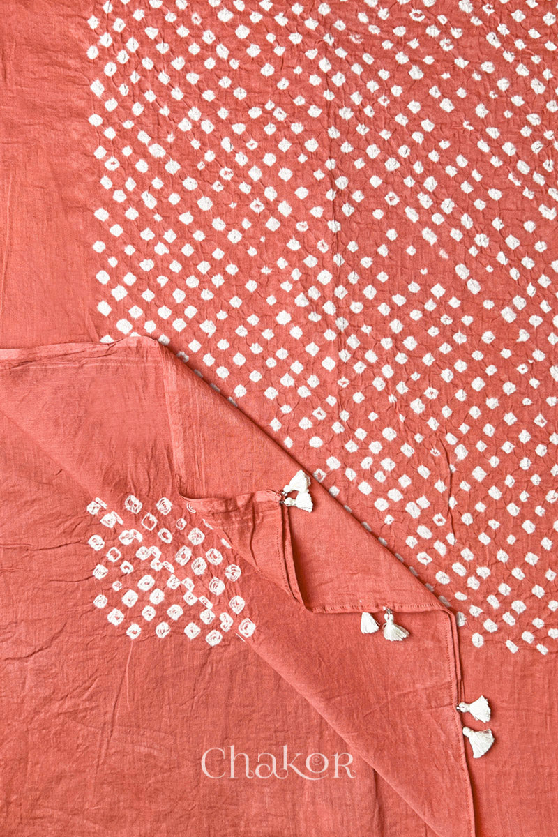Corner detail of Dark Peach Bandhani mul cotton dupatta showing pallu tasseled edge and tie-dye motifs.
