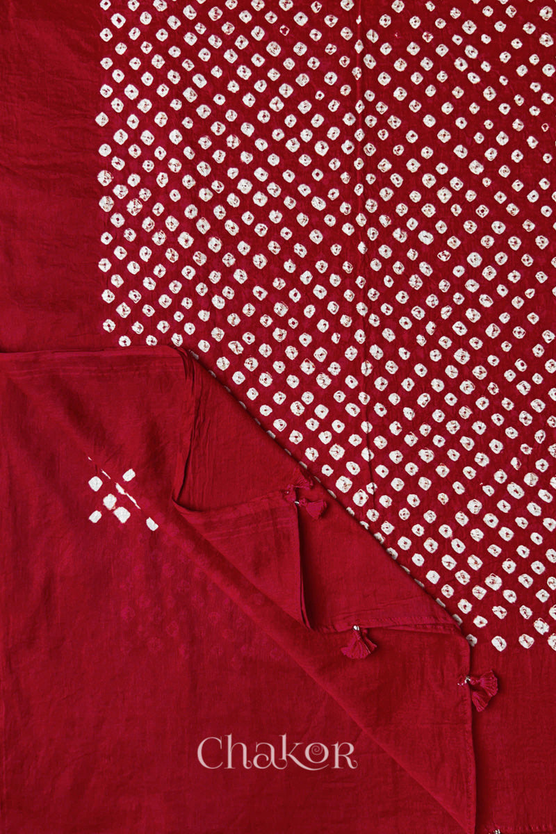 Chakor's red cotton dupatta adorned with white bandhej patterns, featuring decorative tassels at the edges, showcasing intricate craftsmanship.