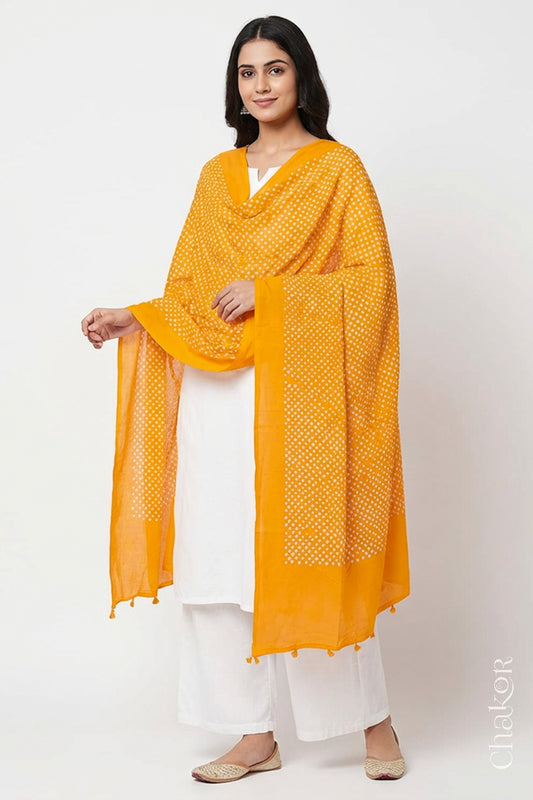 Model wearing Yellow Bandhani mul cotton dupatta with tie-dye dot pattern draped over a white kurta.