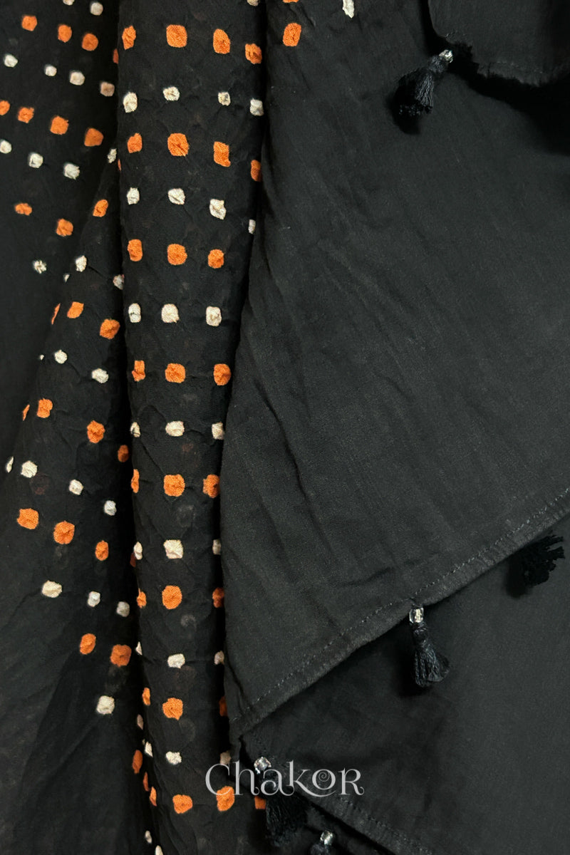 Close up of Authentic Black Bandhani dupatta featuring handmade tassels and dense white & orange tie-dye dot pattern by CHAKOR.