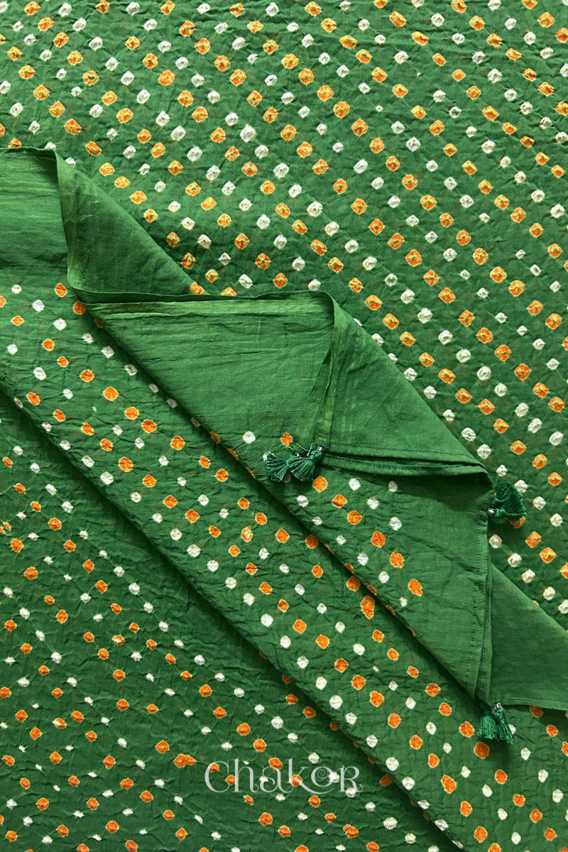 Close up of Authentic Kutch Bandhani dupatta in Mehendi Green featuring handmade tassels and dense white & orange tie-dye dot pattern by CHAKOR.
