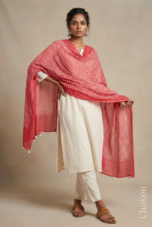 Model wearing dusty red Bandhani mul cotton dupatta with tie-dye dot pattern and pallu edged with tassels draped over a white kurta.