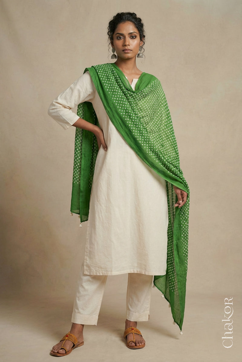 Model wearing mehendi Bandhani mul cotton dupatta with tie-dye dot pattern and pallu edged with tassels draped over a white kurta.