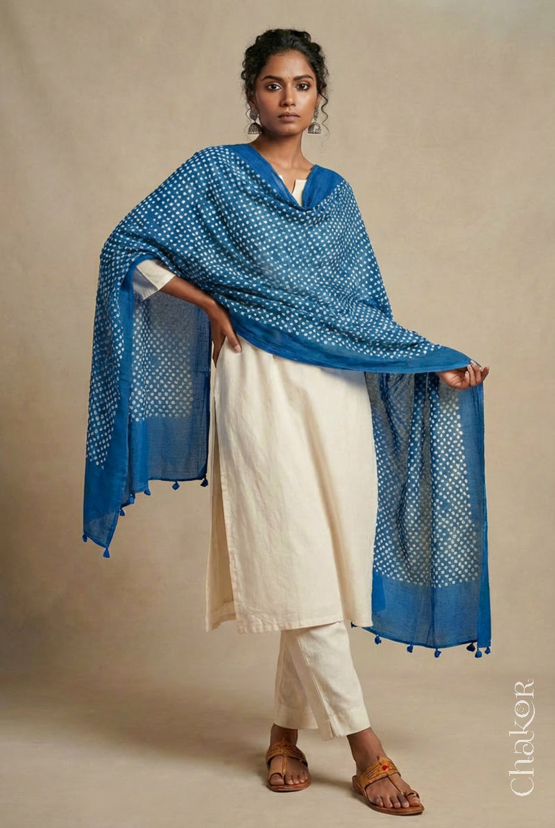 Model wearing indigo blue Bandhani mul cotton dupatta with tie-dye dot pattern draped over a white kurta.