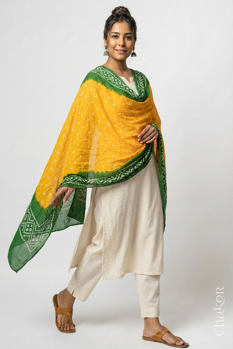 Model wearing yellow and green Bandhani mul cotton dupatta with tie-dye dot pattern draped over a white kurta.