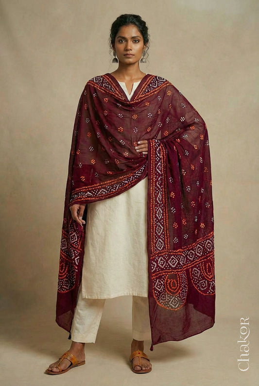 Model wearing maroon Bandhani mul cotton dupatta with tie-dye dot pattern paired with a white kurta.