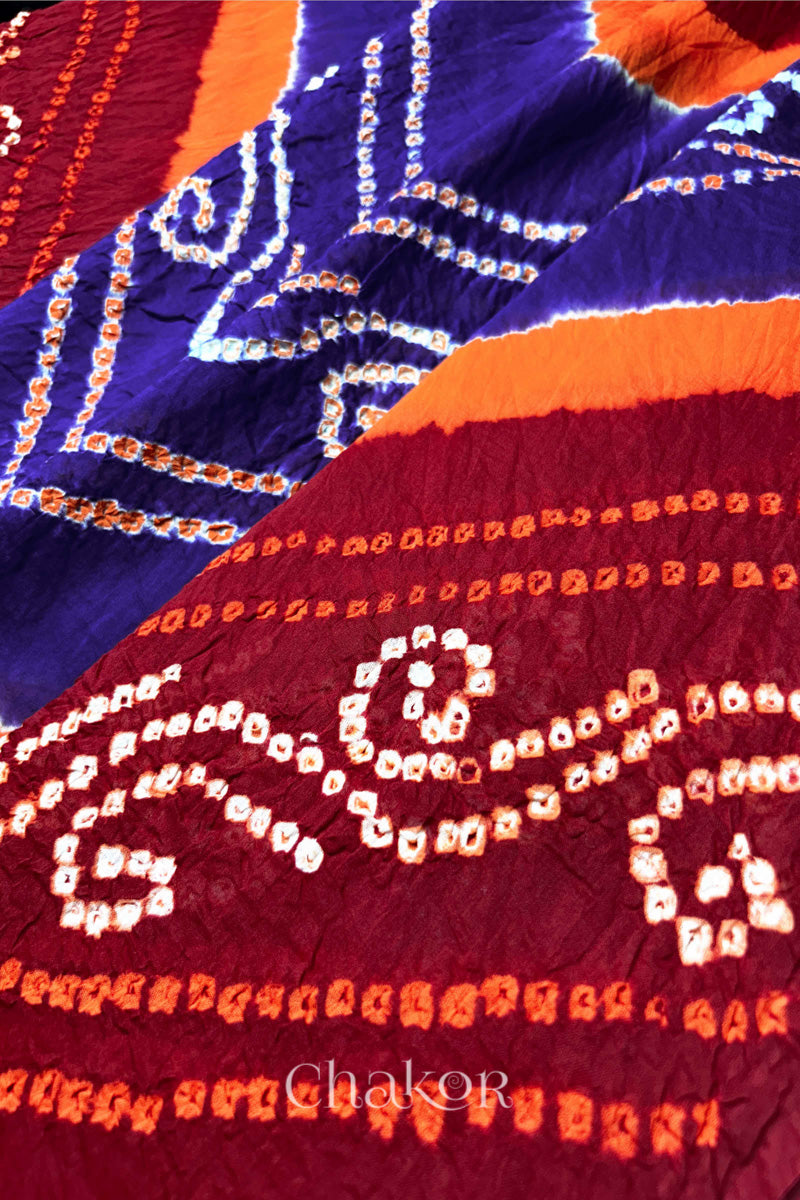 Close-up of red and purple Bandhani mul cotton dupatta showing tie-dye dots and diagonal colour bands.