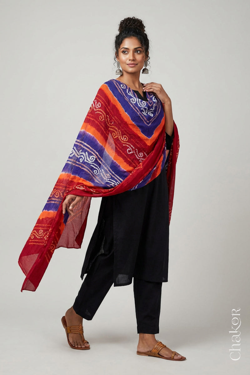 Model wearing red purple mul cotton Bandhani dupatta with multicolour tie-dye dots and striped bands draped over a black kurta.