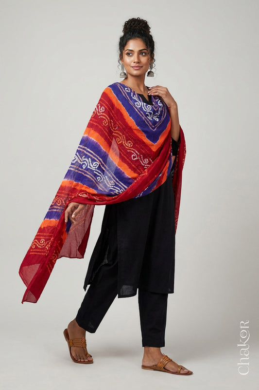 Model wearing red purple mul cotton Bandhani dupatta with multicolour tie-dye dots and striped bands draped over a black kurta.