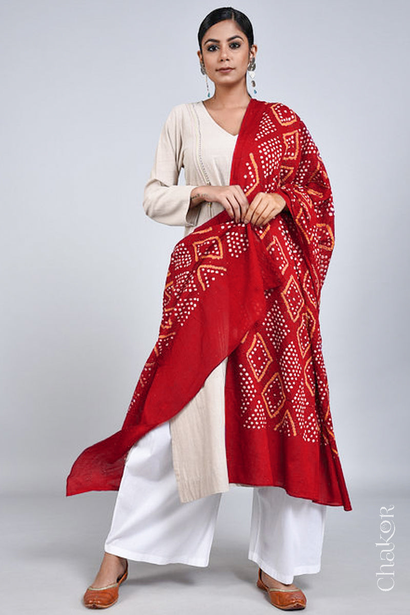 Model wearing a tomato red Bandhani mul cotton dupatta with traditional Chorkat diamond pattern from CHAKOR, draped over an ivory kurta set.