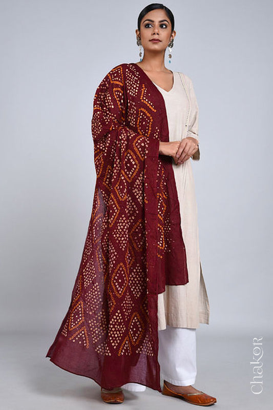 Model wearing a Maroon Bandhani mul cotton dupatta with traditional Chorkat diamond pattern from CHAKOR, draped over an ivory kurta set.