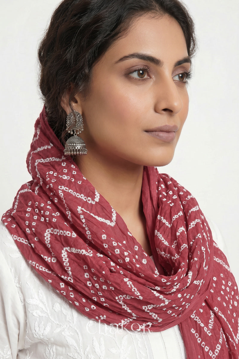 Dusty red Kutch Bandhani mulmul dupatta wrapped around woman's neck.
