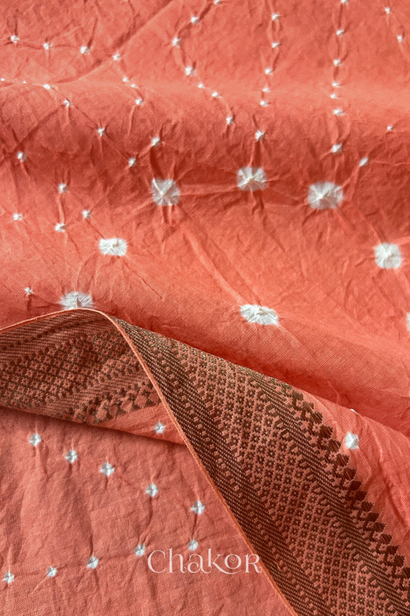 Close-up of white pearl-like dots and the golden zari border detail in the Peach Kutch Bandhani tie-dye pattern.
