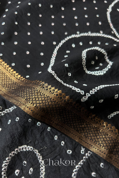 Close-up of white pearl-like dots and golden zari border detail in the Black Kutch Bandhani tie-dye pattern.
