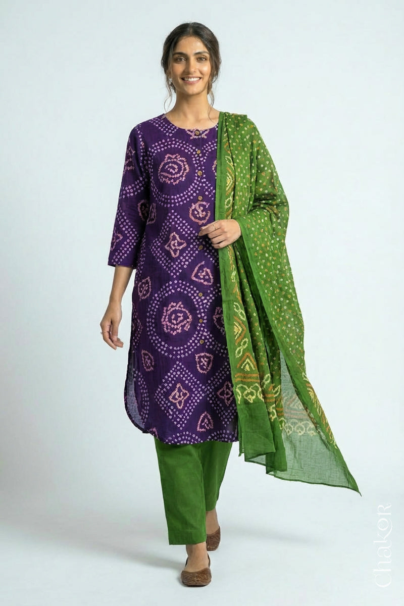 Woman wearing a handcrafted Purple and green Kurta Set and a matching dupatta with traditional bandhani tie-dye patterns.