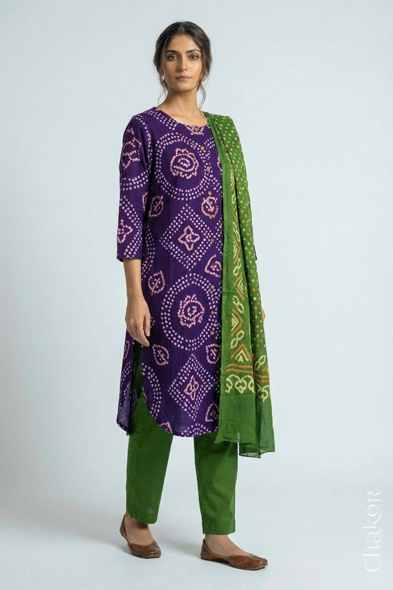 Woman wearing a handcrafted Purple and green Kurta Set and a matching dupatta with traditional bandhani tie-dye patterns.