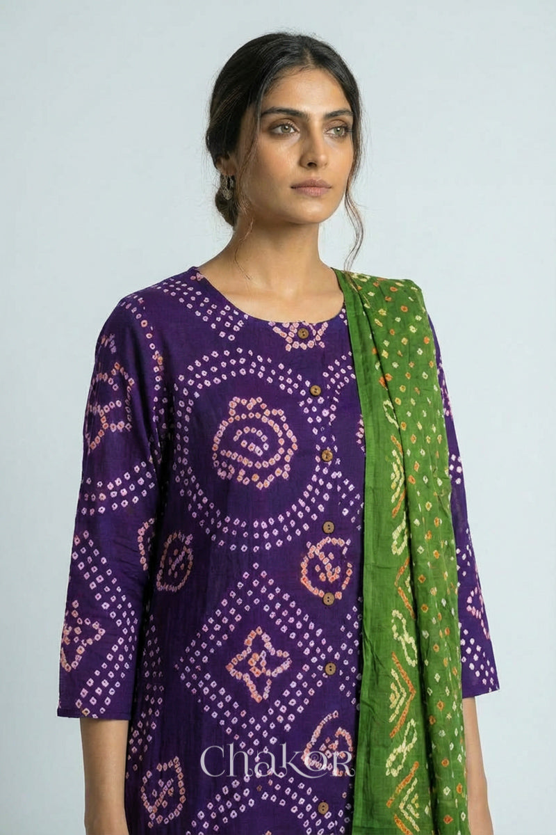 Woman wearing a handcrafted Purple and green Kurta Set and a matching dupatta with traditional bandhani tie-dye patterns.
