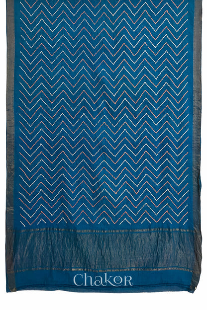 Indigo Blue saree, flat draped with Rai Bandhej zigzag pattern against white background and 'Chakor' brand watermark.
