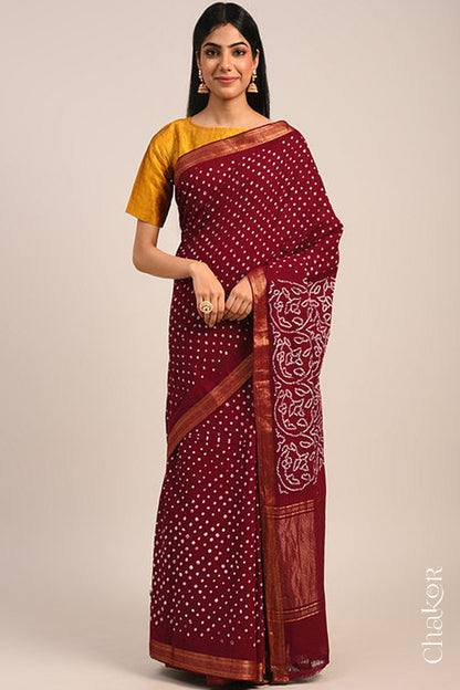 Woman wearing a red bandhani saree with traditional bandhej designs and zari border pallu.