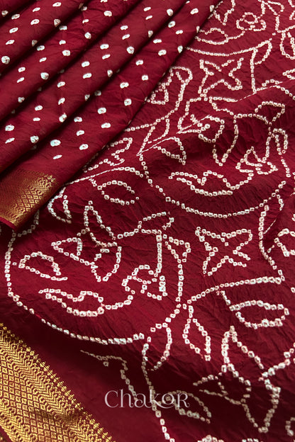 Close-up of red saree, arranged in pleats with rai bandhani and golden border showcasing beautiful craftsmanship.
