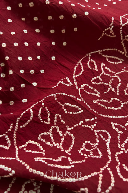 Close-up of red saree with rai bandhej showcasing intricate tie-dye craftsmanship.
