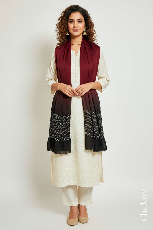 Woman wearing a maroon black shaded bandhani stole on white kurta set.