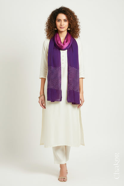 Woman wearing a magenta & purple shaded bandhani stole on white kurta set.
