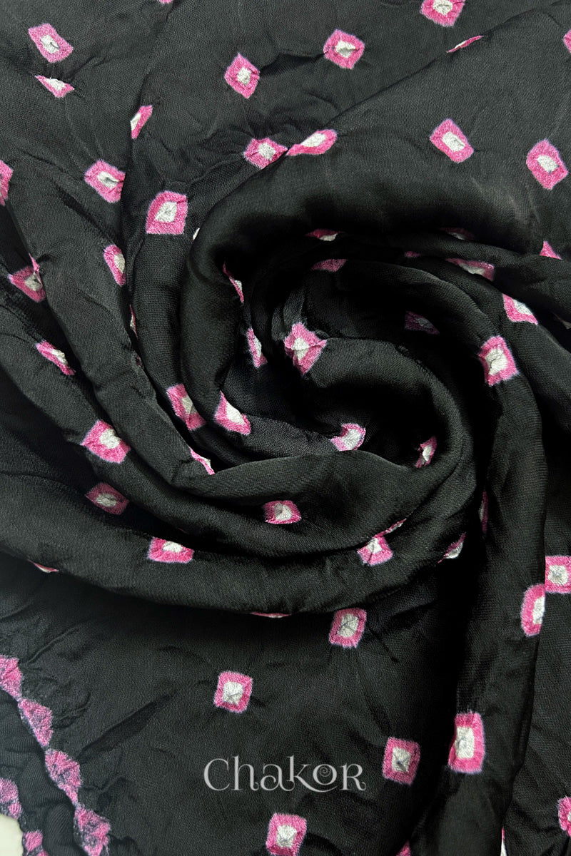 Close-up of black Bandhani modal fabric showing hand tie-dye Chakri motifs and kangri edge arranged in a spiral style.
