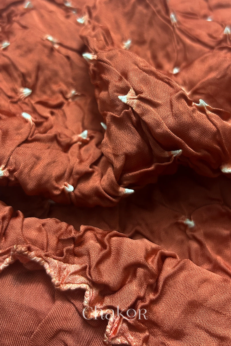 Close-up of coral Bandhani modal fabric showing hand tie-dye Chakri motifs.
