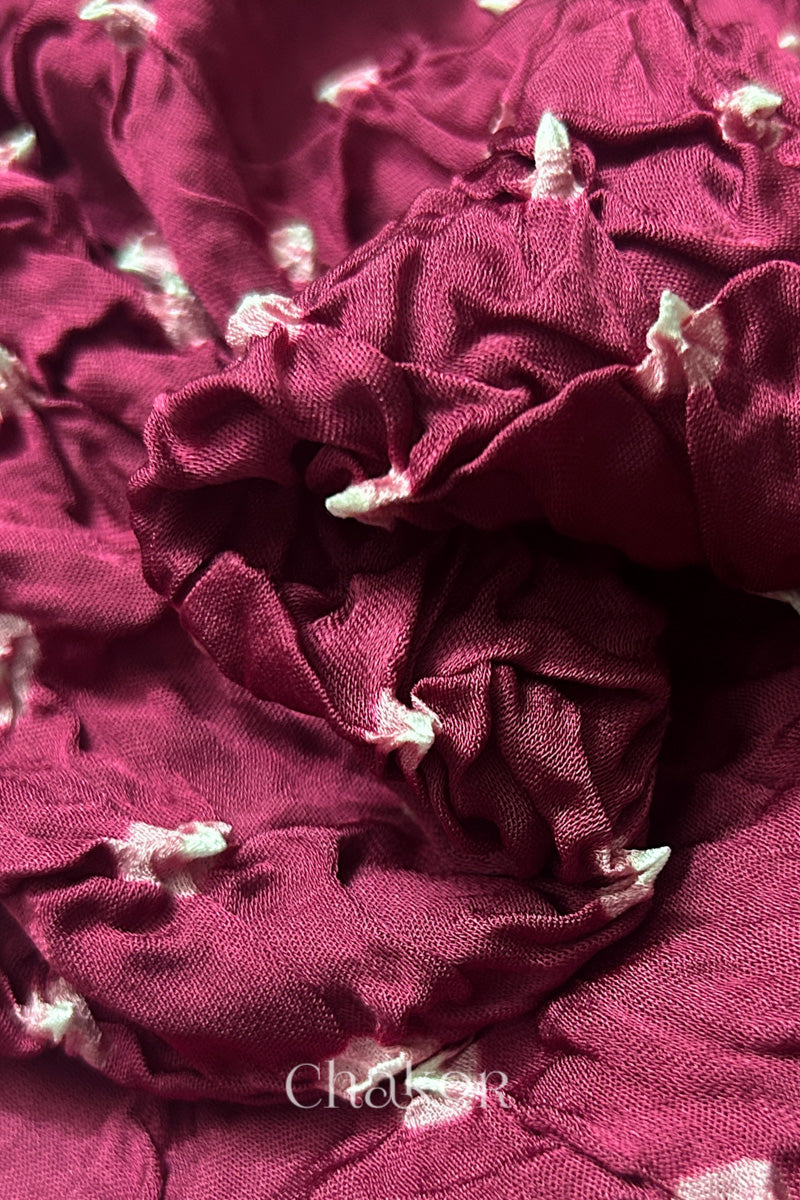 Close-up of raspberry pink Bandhani modal fabric showing hand tie-dye Chakri motifs.
