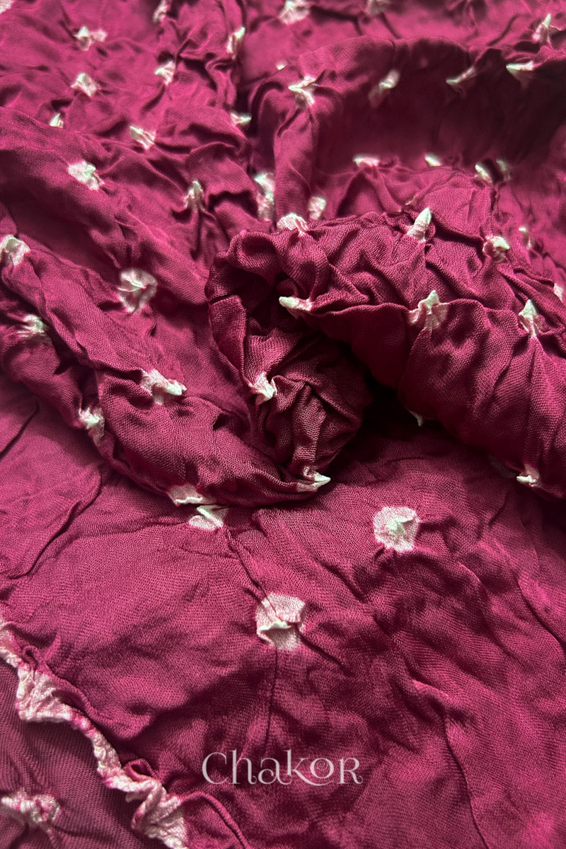 Close-up of raspberry pink Bandhani modal fabric showing hand tie-dye Chakri motifs.
