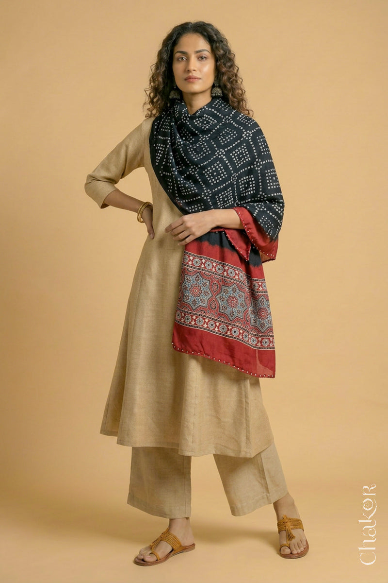 Black Bandhani modal stole styled across shoulders with detailed Madder Red Ajrakh pallu and traditional hand tied pattern.
