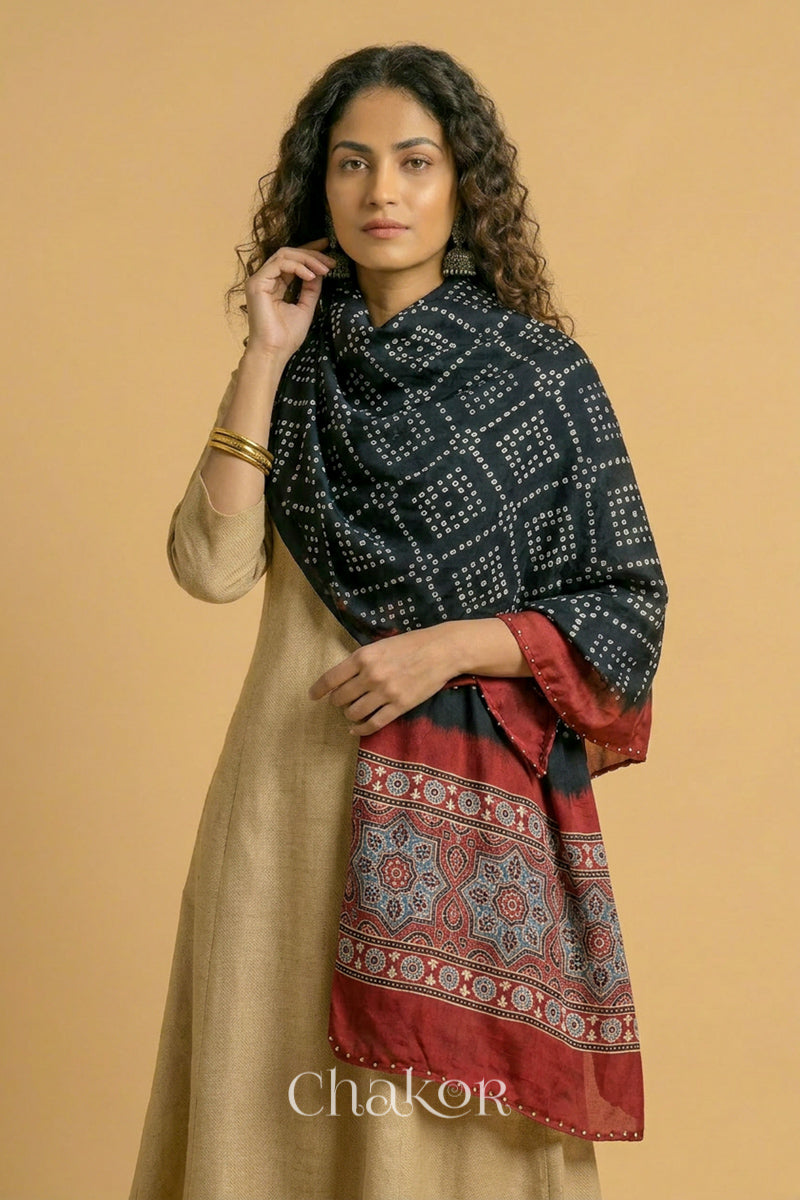 Black Bandhani modal stole styled across shoulders with detailed Madder Red Ajrakh pallu and traditional hand tied pattern.
