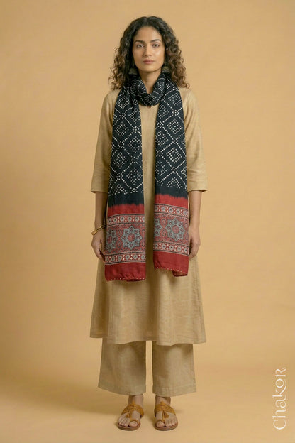 Full length view of handcrafted Black Bandhani stole with iron  Madder Red Ajrakh pallu worn as dupatta wrapped around the neck.
