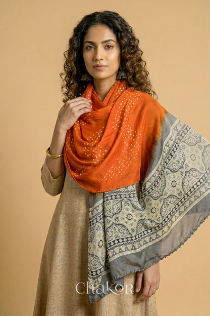 Orange Bandhani modal stole styled across shoulders with detailed Taupe Beige Ajrakh pallu and traditional hand tied pattern.
