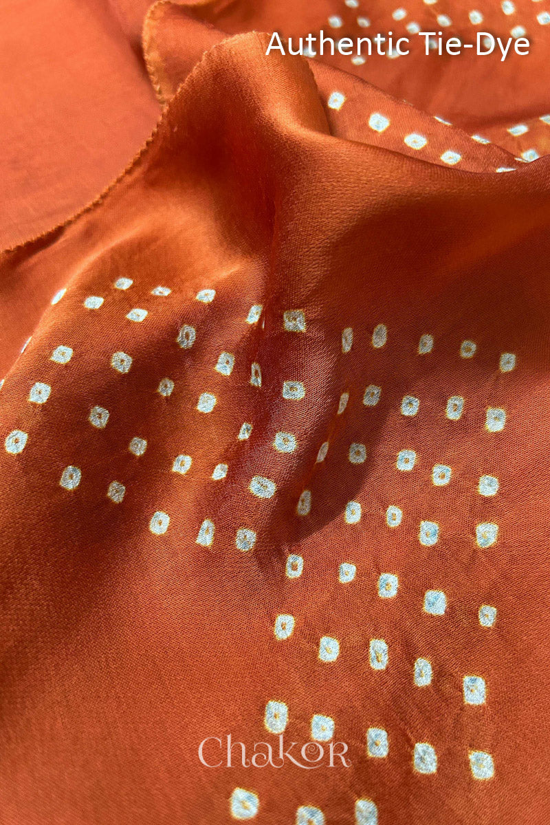 Orange Hand tied Bandhani dots on modal stole with contrast ajrakh pallu detail showcasing fabric texture and softness.
