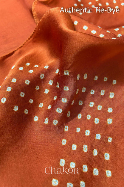 Orange Hand tied Bandhani dots on modal stole with contrast ajrakh pallu detail showcasing fabric texture and softness.
