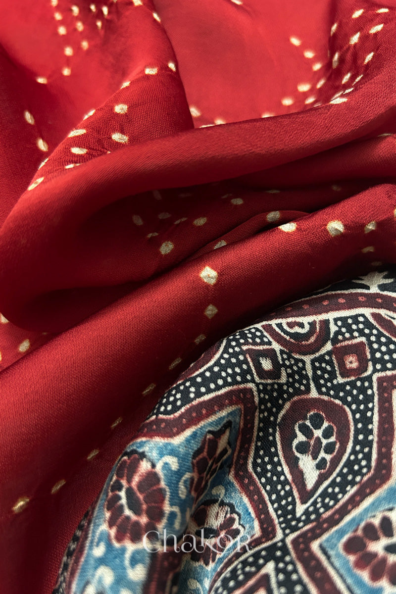 Red Hand tied Bandhani dots on modal stole with contrast ajrakh pallu detail showcasing fabric texture and softness.

