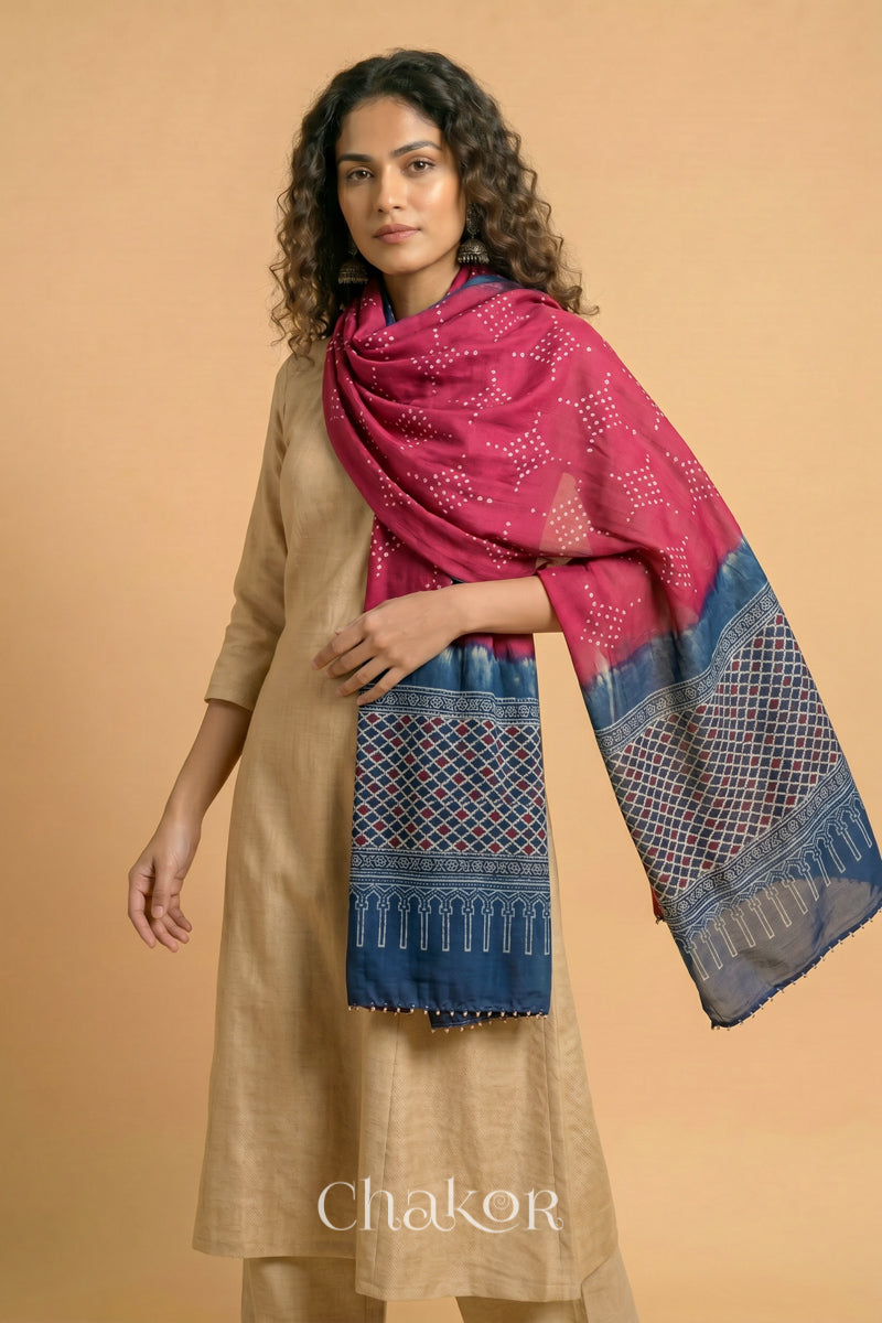 Strawberry Pink Bandhani modal stole styled across shoulders with detailed Indigo Ajrakh pallu and traditional hand tied pattern.
