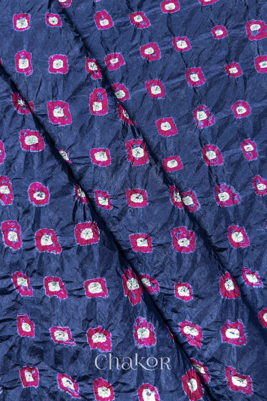 Blue Grey Mulberry silk fabric showcasing dual colour Pink bandhani patterns with folds and Chakor brand watermark.
