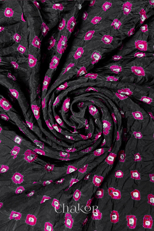 Black Mulberry silk fabric with dual colour Pink bandhani dots, arranged in a swirling design  & Chakor brand watermark.
