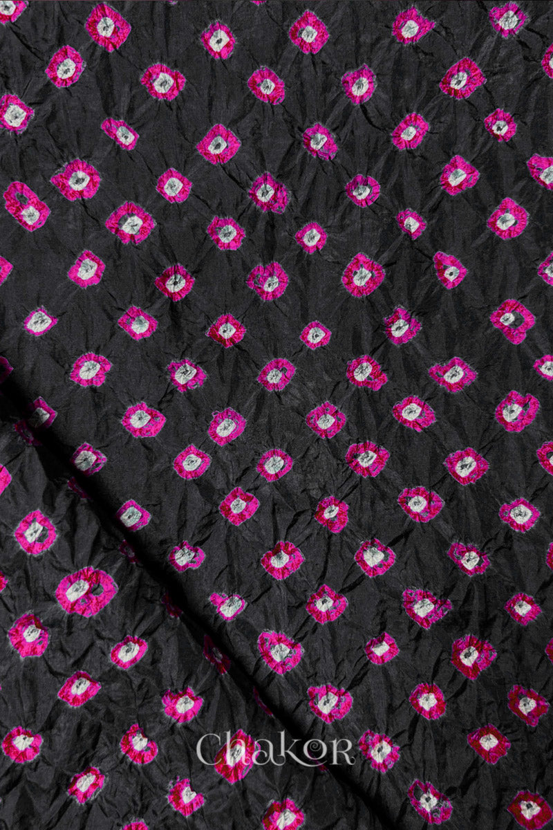 Black Mulberry silk fabric showcasing dual colour Pink bandhani patterns with folded corner and Chakor brand watermark.
