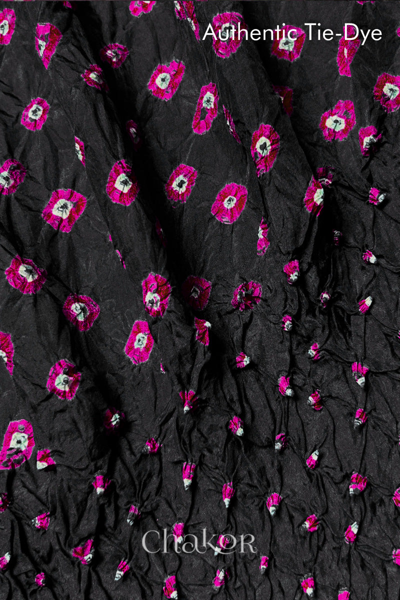 Close-up of Black mulberry silk fabric with Pink and white patterns, featuring texture of authentic bandhani patterns.
