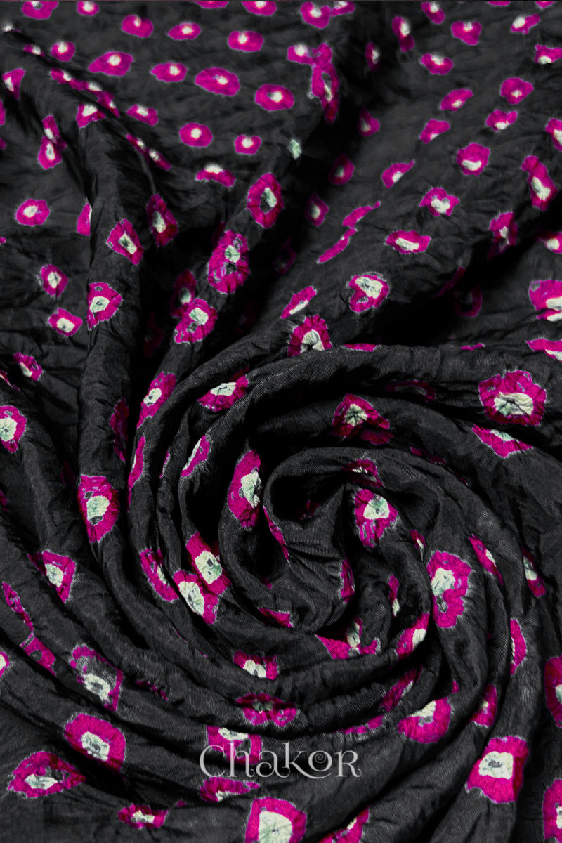 Black Mulberry silk fabric with dual colour Pink bandhani dots, arranged in a swirling design  & Chakor brand watermark.
