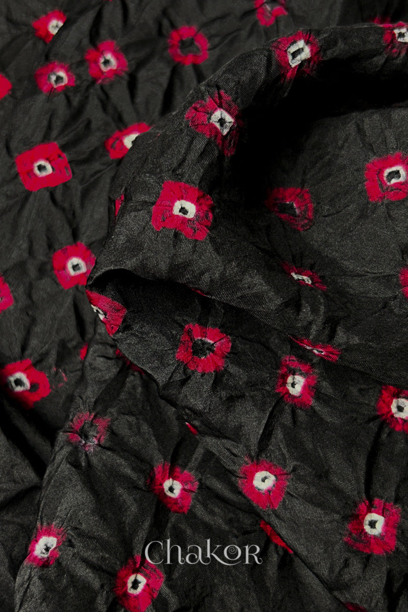 Close-up of Black fabric with Red and white bandhani patterns, featuring texture and sheen of soft mulberry silk fabric.
